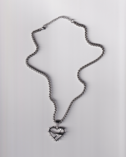 Silver necklace with a heart-shaped pendant on a light gray background
